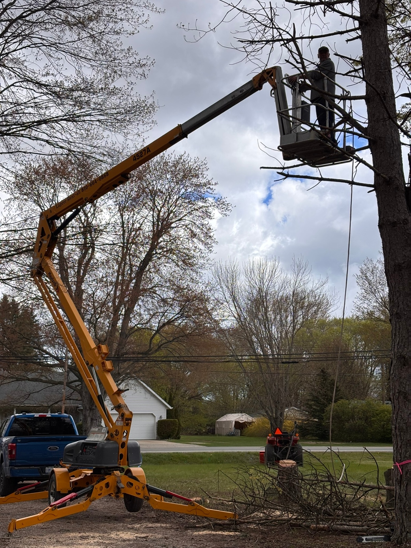 Bucket lift trimming hazardous limbs from a large tree in Attica, MI